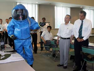 化学防護服の説明を聞く参加者 - APEC関連会合、県警と公共交通機関が会議