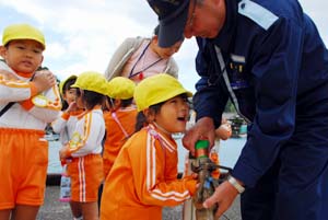 ホースの重さに驚く女の子 - 下津幼稚園園児が海保巡視船見学