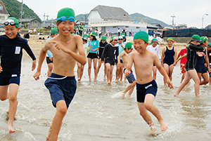 一斉に海の中へと走る加太小学校の児童