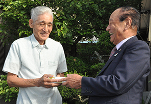 井村会長㊨から祝い品を受け取る西川さん