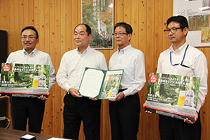 関島本部長（左から２人目）が下副知事（同３人目）に申出書を手渡した