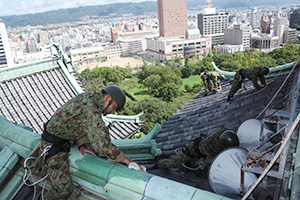 屋根に上り清掃作業を進める自衛隊員ら