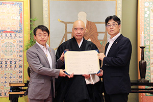 協定書を手にする（左から）平野町長、添田宗務総長、神崎所長