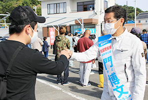 和歌浦漁港で支援者とグータッチをする門候補（２４日）