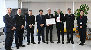 瀧川会長（右から４人目）が樫畑理事長（同３人目）に目録を贈呈