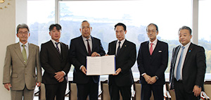 協定書を手にする吉本会長（左から３人目）、尾花市長（同４人目）と県造園建設業協会の皆さん