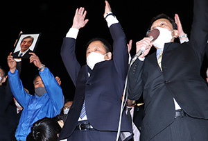 中村前市長の遺影を掲げる中、支持者と万歳する岸本さん（右から２人目）＝２月２７日午後９時３９分