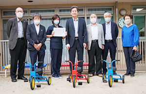 贈呈した三輪車を前に和歌山中ロータリークラブのメンバーと宮本会長（左から４人目）、本田園長代理（同３人目）