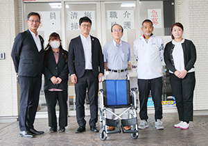 寄贈した車いすを前に矢野支店長（左から３人目）と家本取締役（同４人目）
