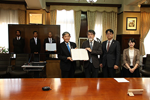 協定書を手にする仁坂知事（中央）、藤井総長（画面内右端）ら