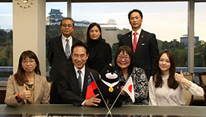 「熊讃」を手に笑顔の李局長（前列左から３人目）一行と尾花市長（同２人目）ら