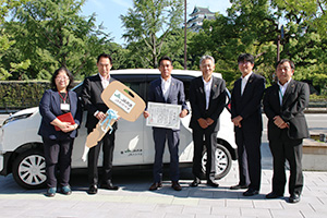 寄贈した電気自動車の前で坂東組合長（左から３人目）、尾花市長（同２人目）ら