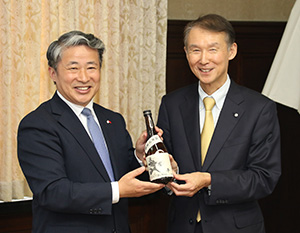 薛総領事㊧から贈り物の酒を受け取る岸本知事