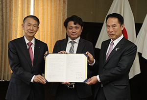 協定書を手に（左から）岸本知事、北村代表取締役、尾花市長