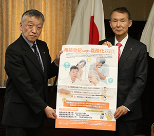 相続登記の申請義務化を周知するポスターを手に伊澤会長㊧と岸本知事